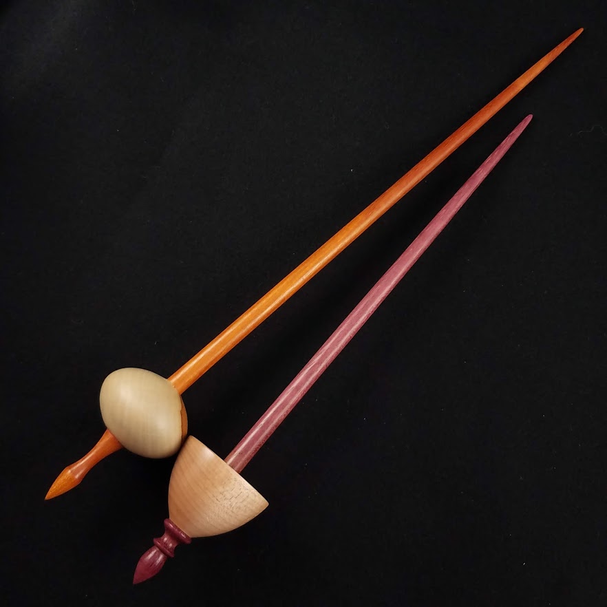 A full-length Spanish Peacock bead spindle next to a pocket Tibetan spindle