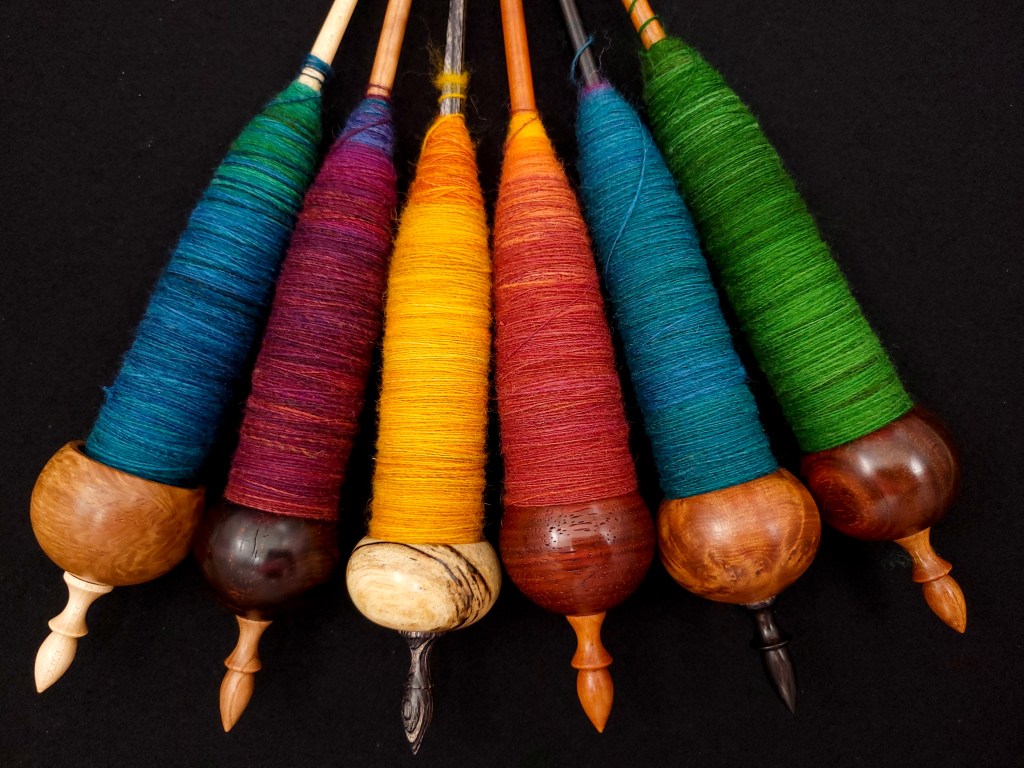 The six Spanish Peacock ninja spindles at the end of the spinalong, all full of spun yarn