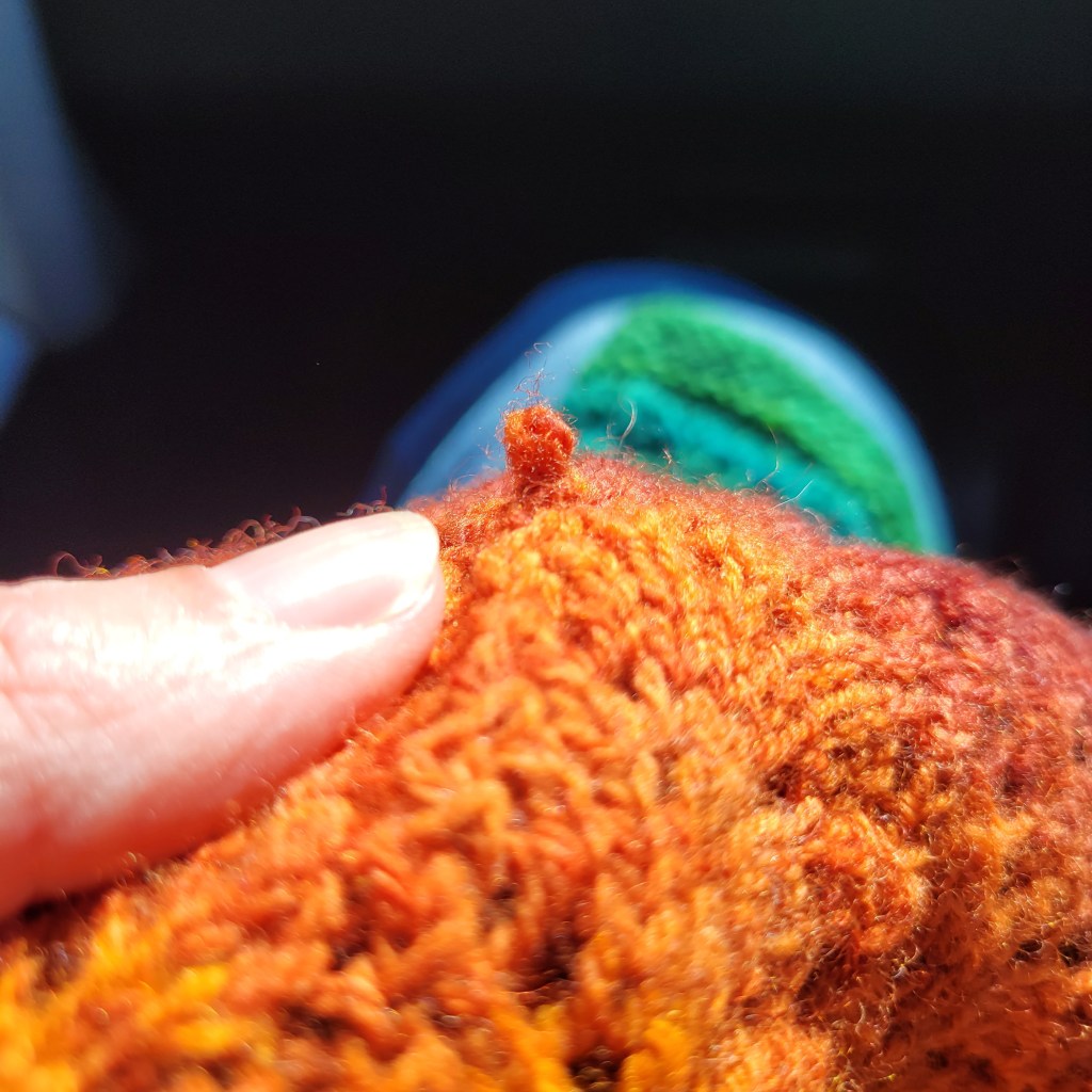 A loose stitch in the middle of my knitted cowl demonstrates that I am STILL a terrible knitter