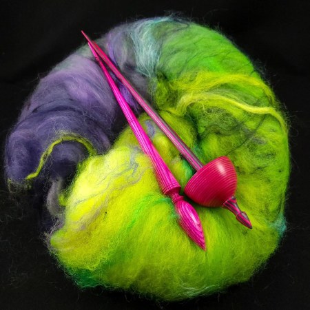 Two spindles laying on a batt of fiber