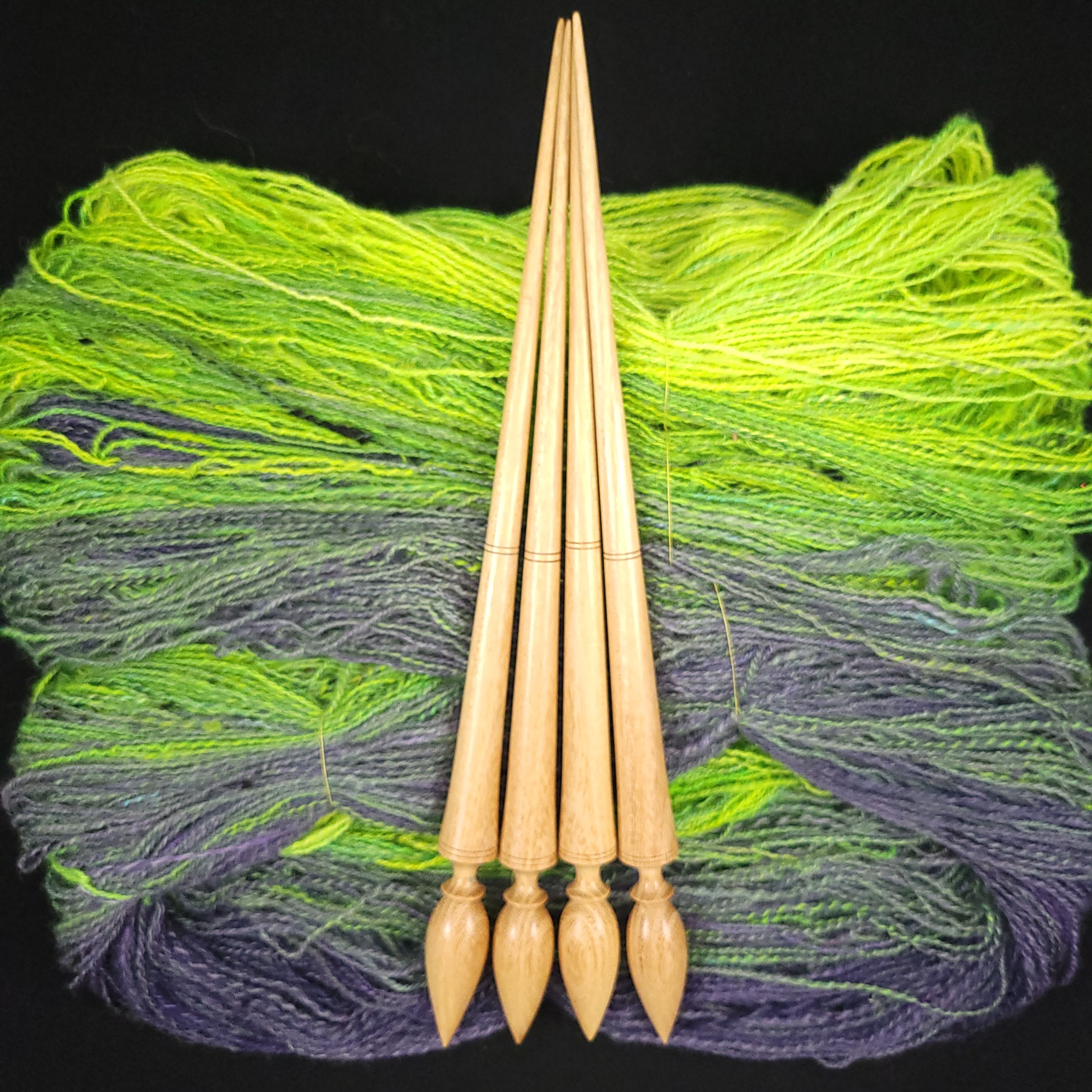 Four bare spindles laying on top of the finished yarn