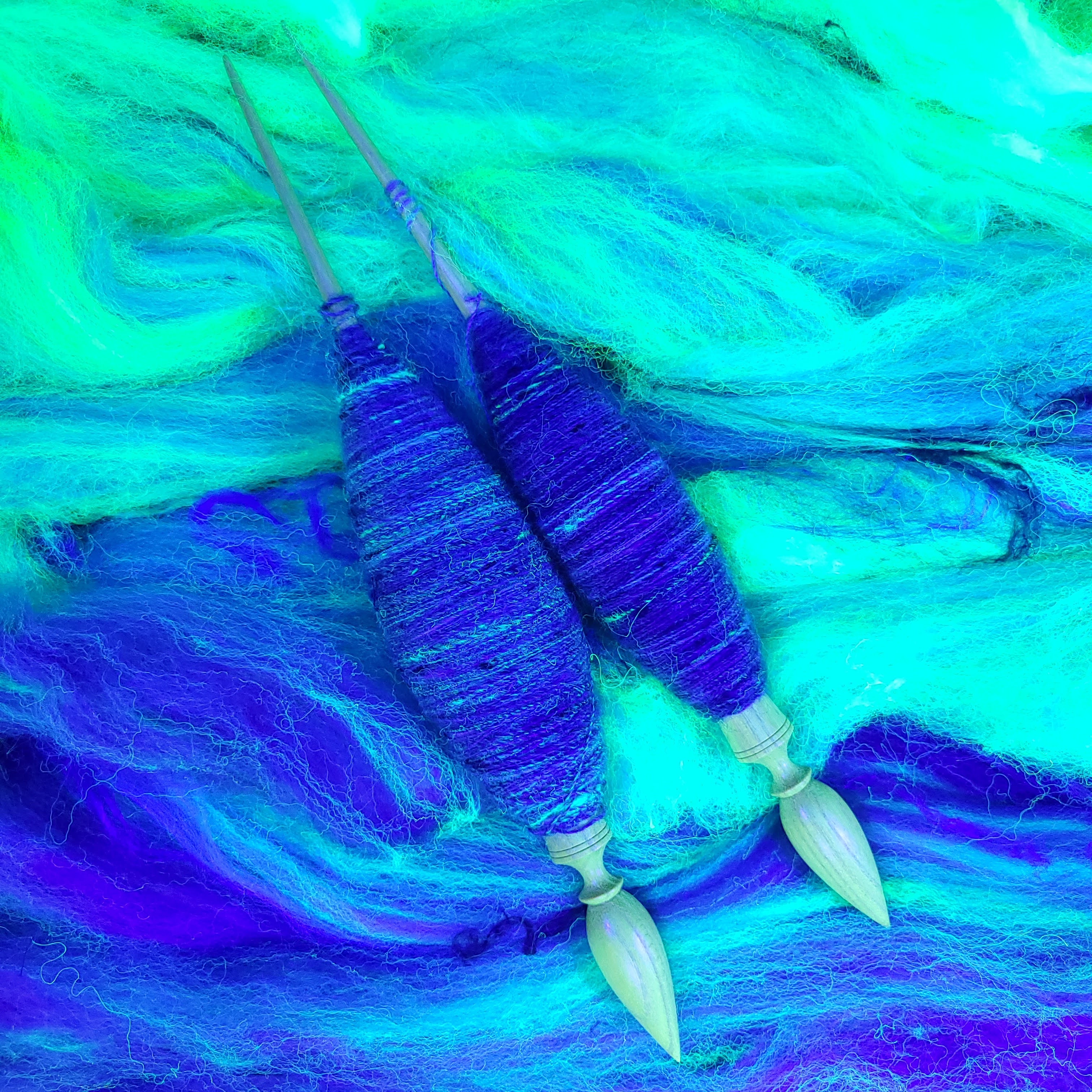 Two spindles full of yarn laid across the remaining batt