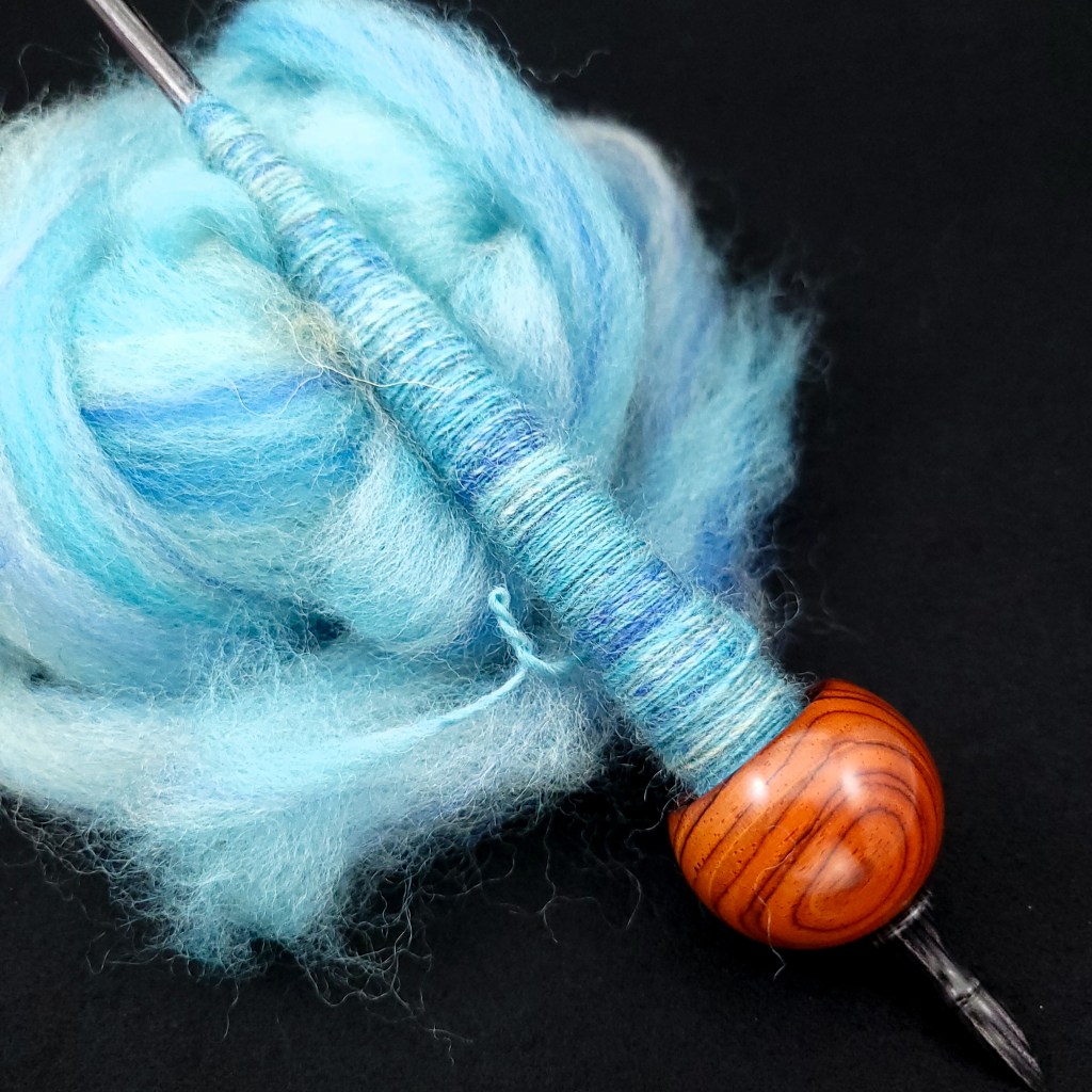 A supported spindle with blue fiber partially spun