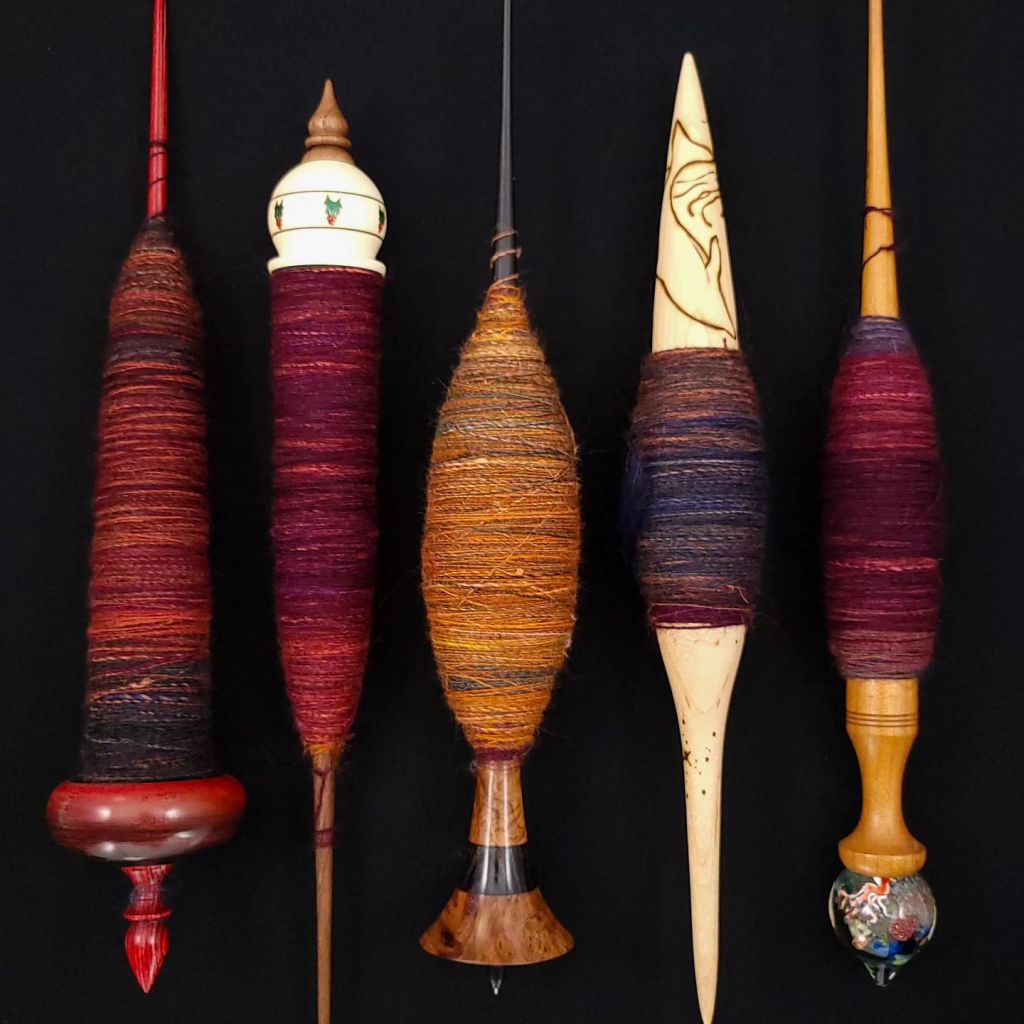 Five supported spindles full of spun singles in the Harlequin colorway by Inglenook Fibers
