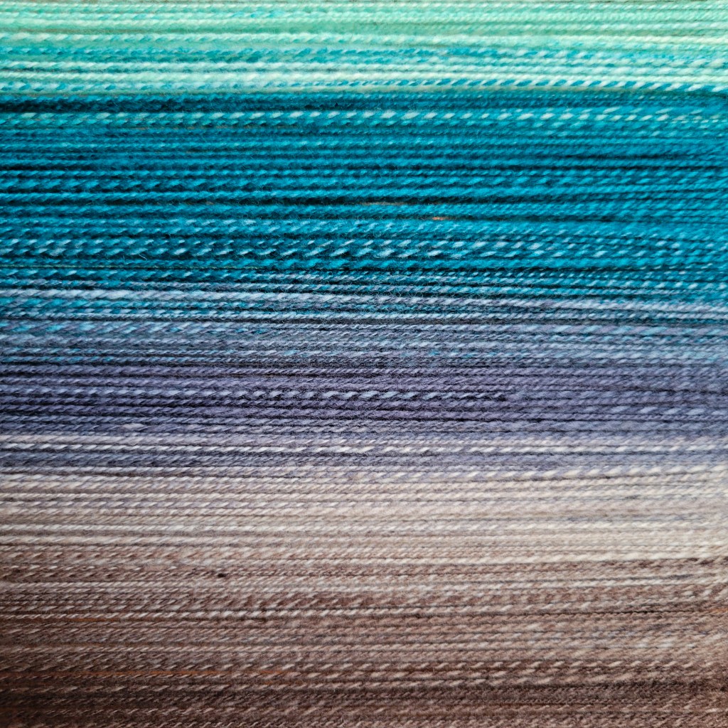 A picture of yarn, showing the gradient from mint, to blue, gray and then brown. 