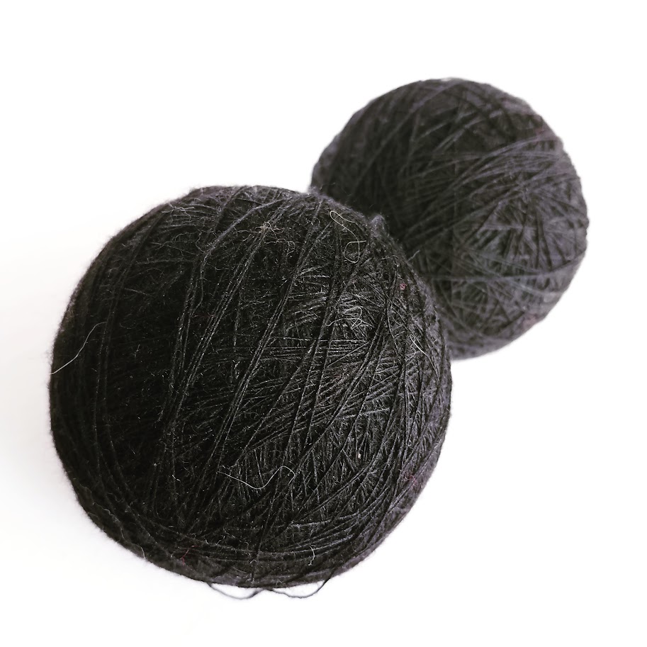 Two black balls of yarn on a white background