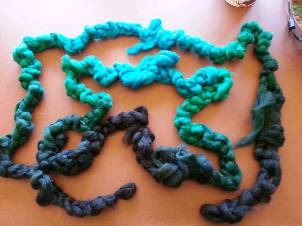 Smaller braids of fiber show a progression of color from black to green to blue and back again