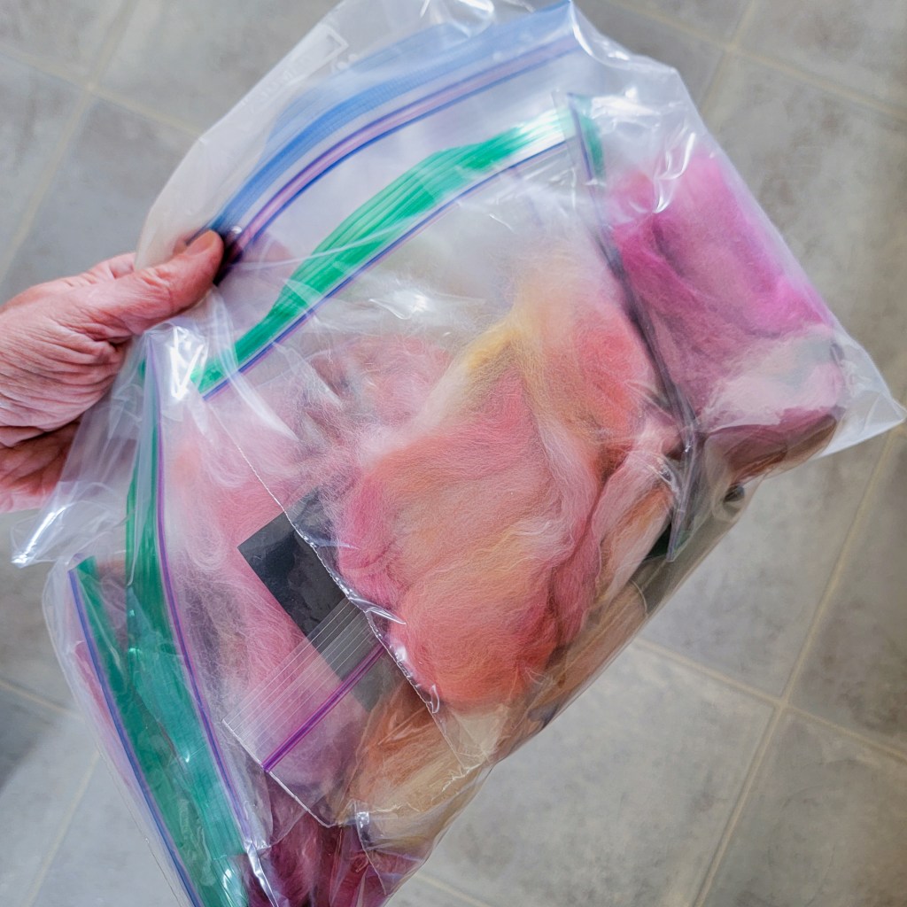 A hand holds a reclosable bag full other reclosable bags which contain a specific section of fiber.